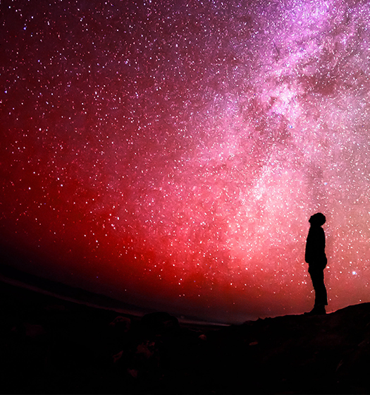 Person looking up at sky full of starts to illustrate McGill focus on breaking down barriers to research to understand the universe