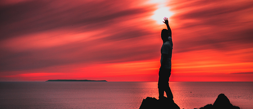 Person standing by ocean at sunset