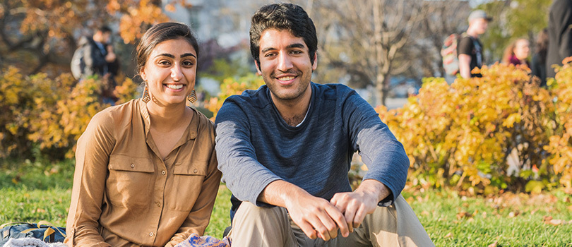 Two students in front of an autumn background 