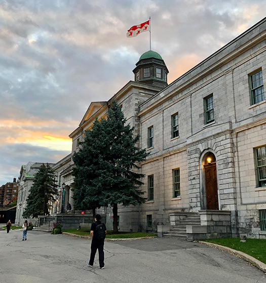 Plusieurs étudiants marchant devant le bâtiment des arts au crépuscule