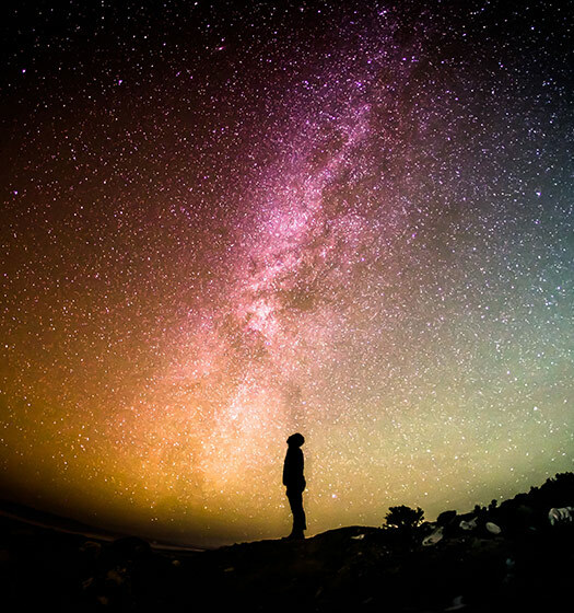 Une personne se tenant sur une colline et regardant les étoiles