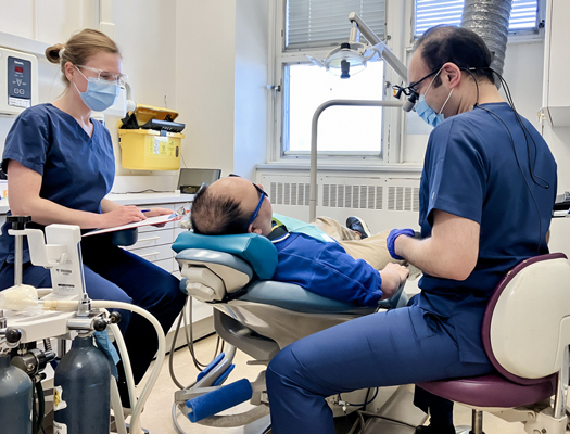 Une groupe de personnes travaillant autour d'un patient sur un fauteuil dentaire