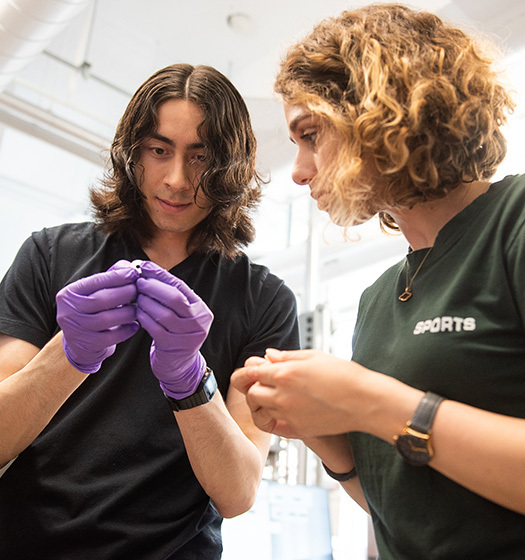 Un étudiant avec des gants violets et une étudiante