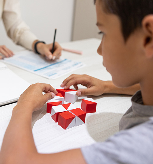 Un enfant travaille sur un puzzle et quelqu'un prend des notes.