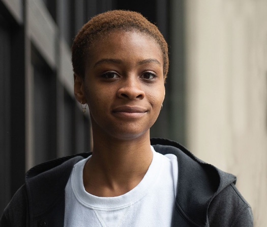 Une personne aux cheveux courts portant une veste noire