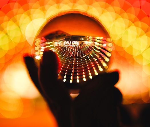 Une main tenant une boule de cristal avec des lumières en arrière-plan