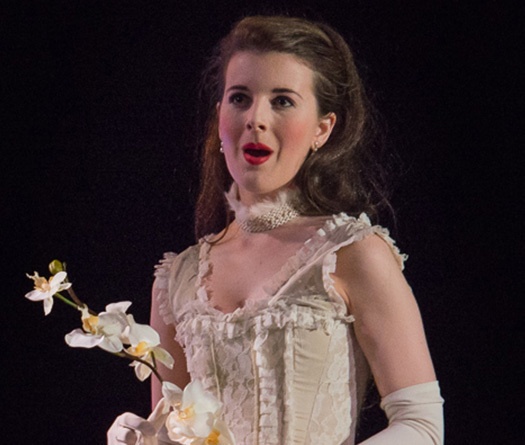 Une femme en robe blanche chantant en tenant une fleur
