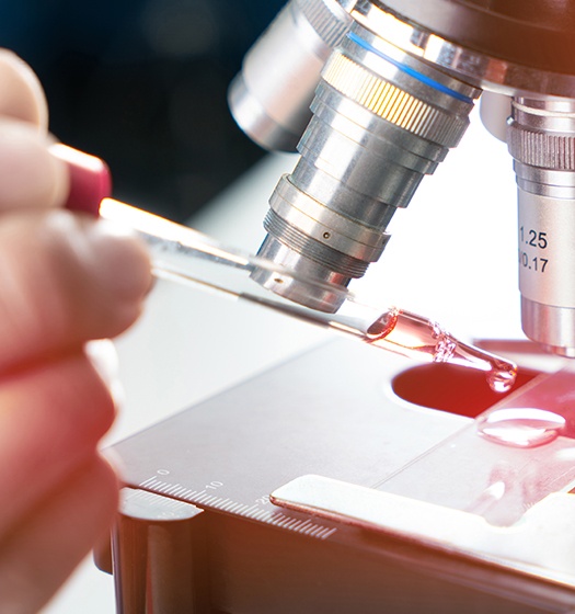 Un chercheur utilise un compte-gouttes pour déposer un spécimen sur une lame de microscope
