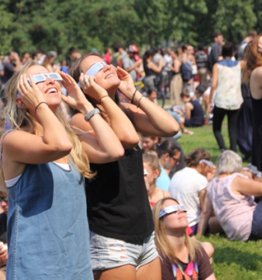 Une foule regardant le ciel avec des lunettes pour éclipses.