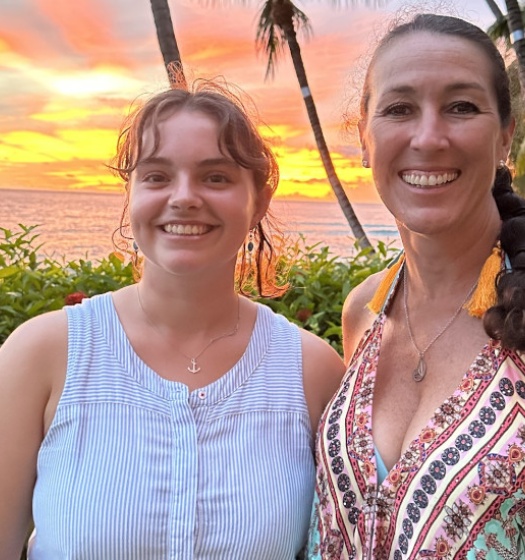 Deux femmes debout l'une à côté de l'autre avec un coucher de soleil en arrière-plan.