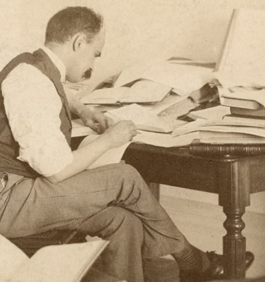 Une personne assise à un bureau avec une pile de livres.